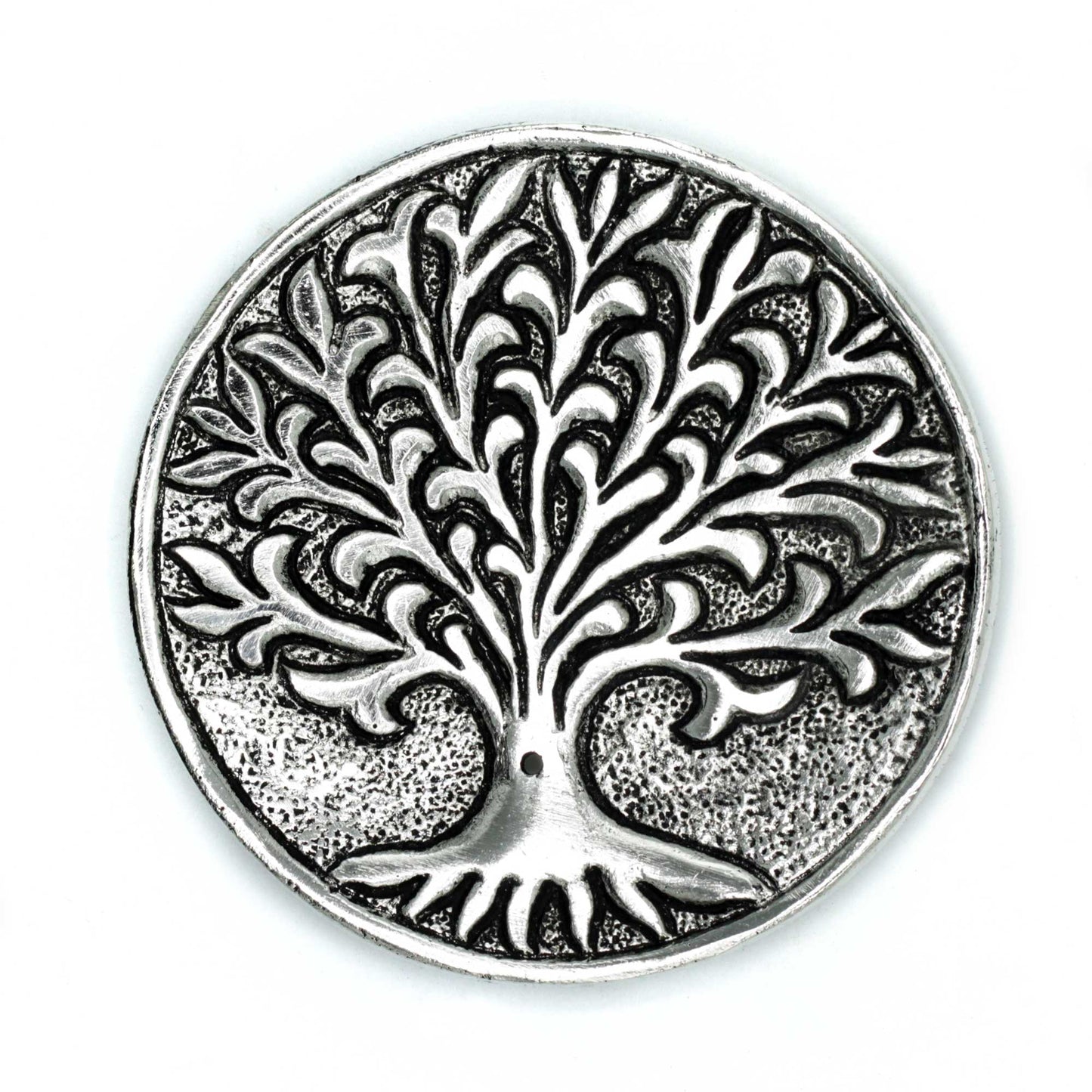 A round metallic medallion features a raised tree with intricate, swirling branches. The textured background enhances its detailed design, creating a sense of depth against the smooth surface.