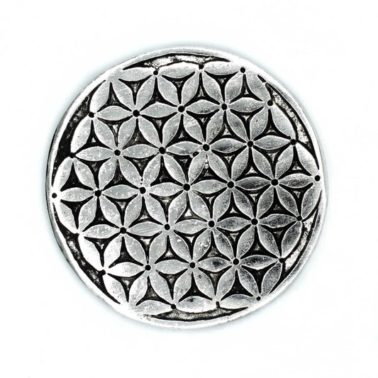 A round metallic object features an intricate pattern of interlocking geometric shapes. It appears stationary against a plain white background, highlighting its detailed design.