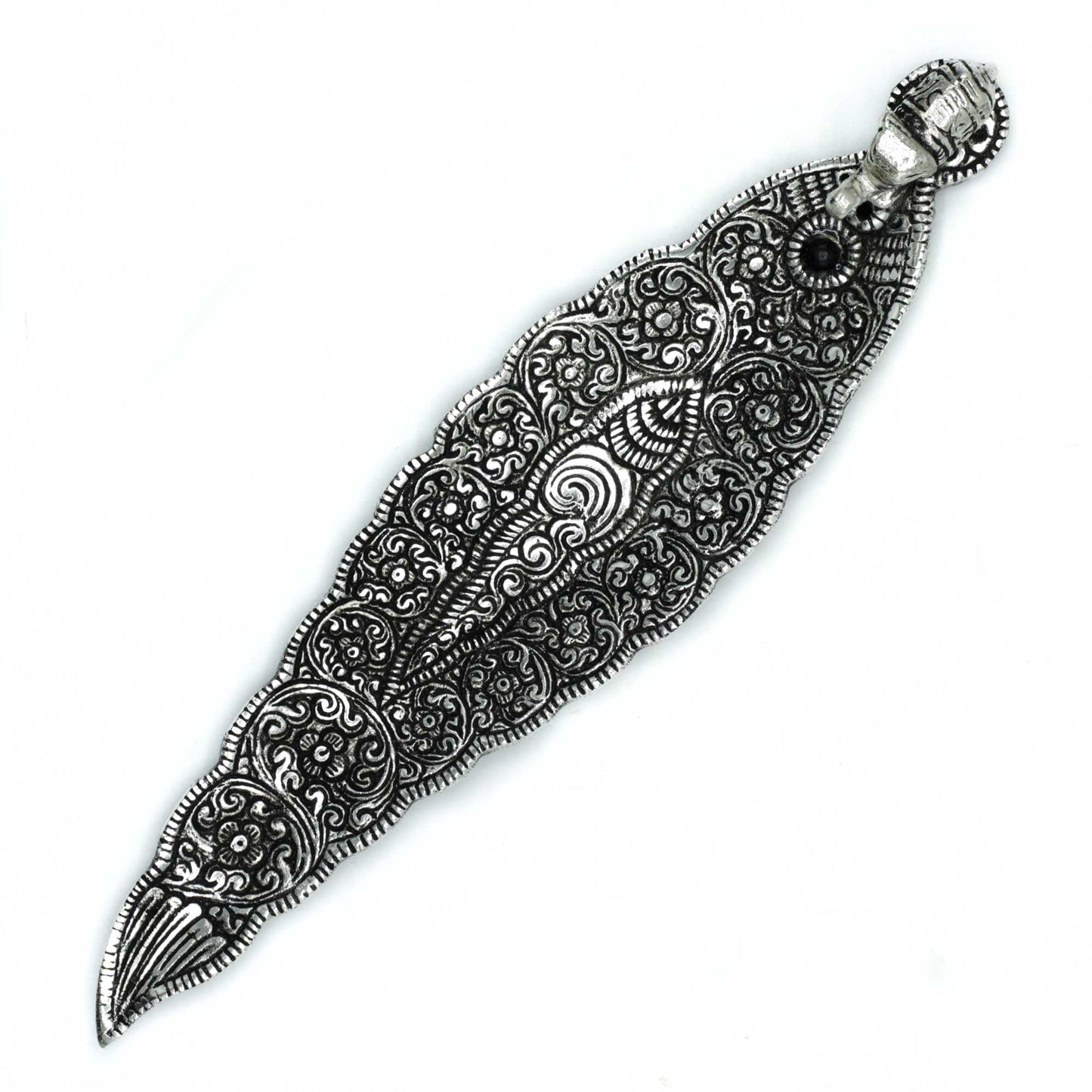 Ornate leaf-shaped silver ornament, intricately engraved with swirling floral patterns, set against a plain white background.