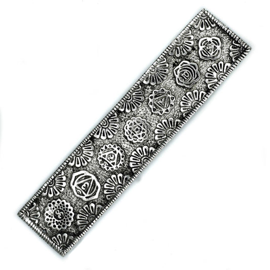 A rectangular metal bookmark displays intricate, embossed floral and geometric patterns, alternating in a repeating sequence, against a textured background.