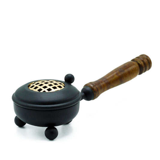 A small, black metal brazier with a wooden handle rests on three round legs; its top features a lattice-patterned grate, set against a plain white background.