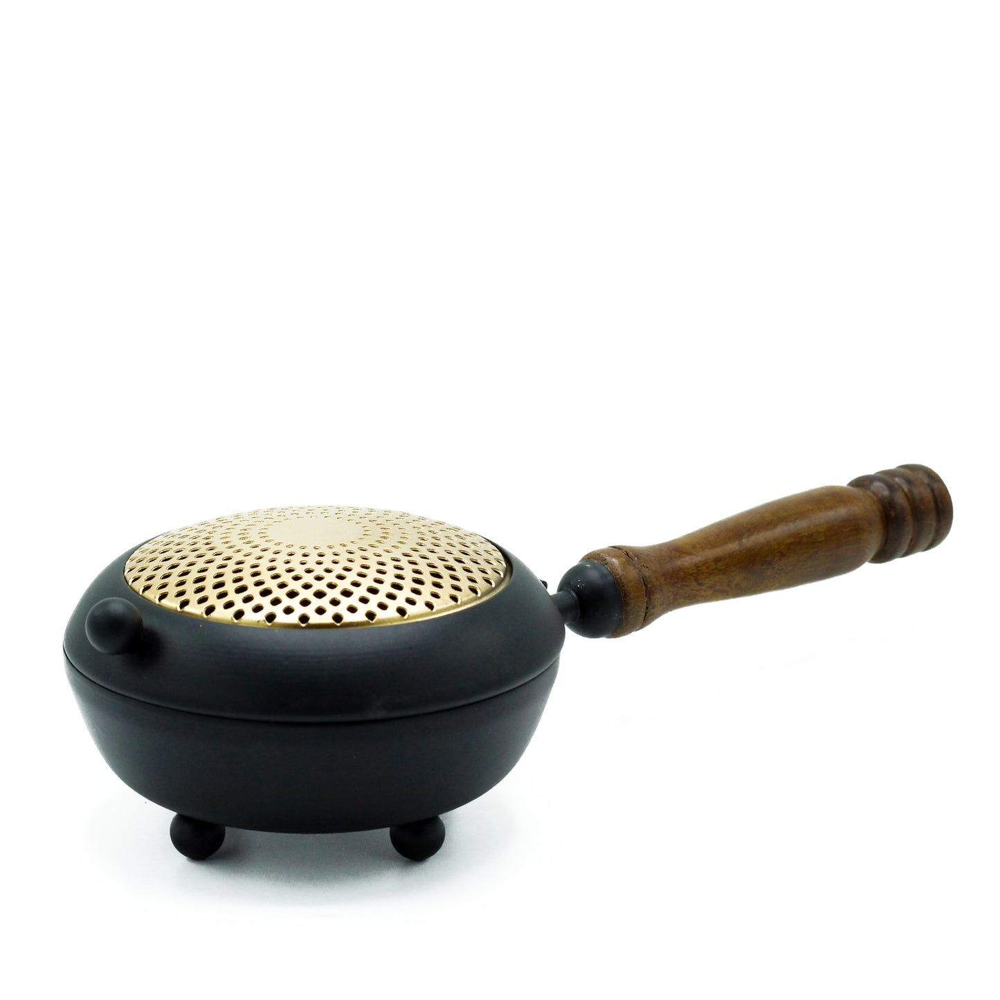 A black metal brazier with a perforated brass lid rests on small legs, featuring a wooden handle. It is placed on a white background.