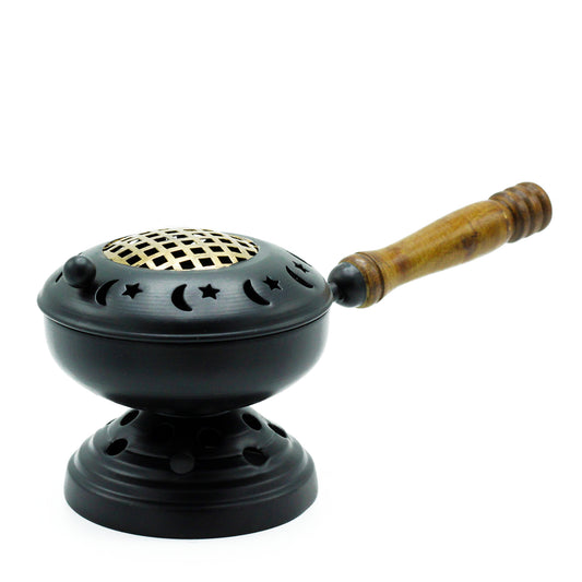 A black metal incense burner features star and moon cutouts, with a wooden handle attached. It rests on a circular base, creating an elegant, celestial-themed design.