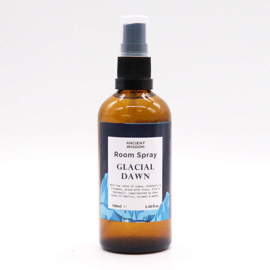 A brown glass bottle containing room spray sits on a white background. The bottle is labeled "ANCIENT WISDOM Room Spray GLACIAL DAWN" and lists fragrance notes.