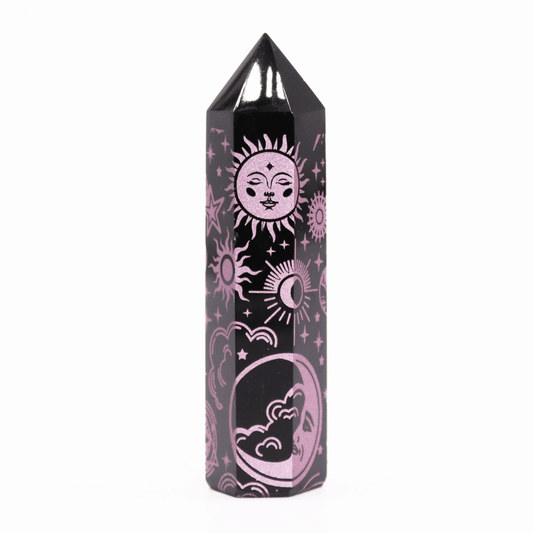 A black, faceted crystal tower features pink celestial designs, including sun and moon faces, stars, and clouds, standing vertically on a white background.