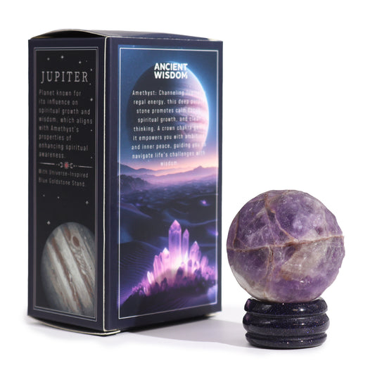 An amethyst sphere rests on a blue goldstone stand. It sits next to a box describing its properties and Jupiter's influence on spiritual growth. The background is white.