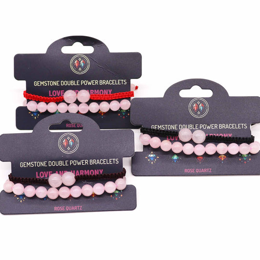 Three pairs of bracelets, each with pink gemstone beads and a colored string, are displayed on individual cards. Each card reads “GEMSTONE DOUBLE POWER BRACELETS, LOVE AND HARMONY, ROSE QUARTZ.”