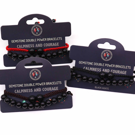 Three beaded bracelets, displayed on cards, present calmness and courage. Each bracelet features black agate beads and string; one has a red string, two have brown. The cards state "GEMSTONE DOUBLE POWER BRACELETS CALMNESS AND COURAGE" and "BLACK AGATE".