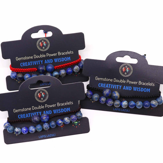 Three gemstone bracelets, displayed on black cards, feature lapis lazuli beads and red or black cords. The cards advertise "Gemstone Double Power Bracelets, CREATIVITY AND WISDOM," and identify the stone as "LAPIS LAZULI" or "LAPIS LA."