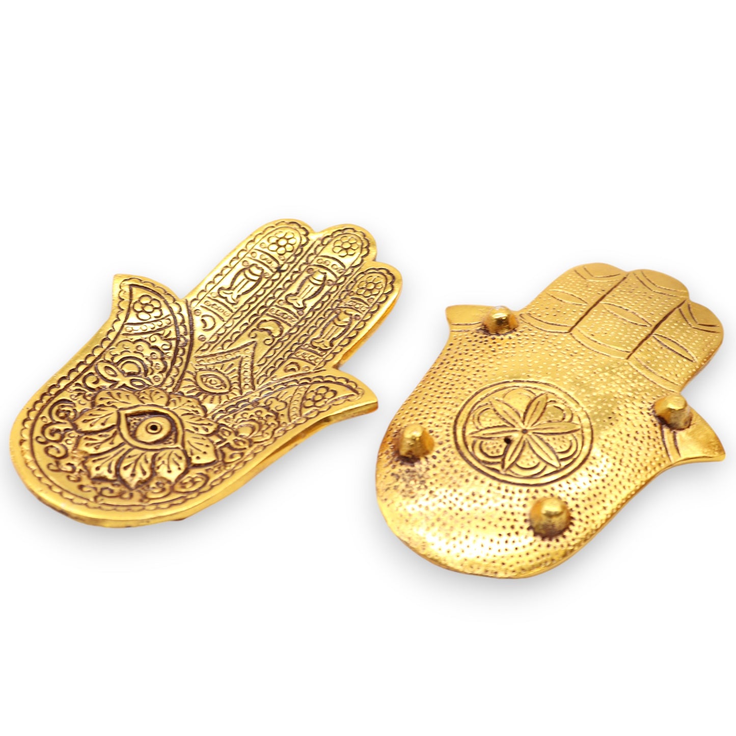 Two ornate golden hamsa wall hooks lie on a white surface; one displays intricate floral patterns, while the other features a central flower design and three protruding knobs.