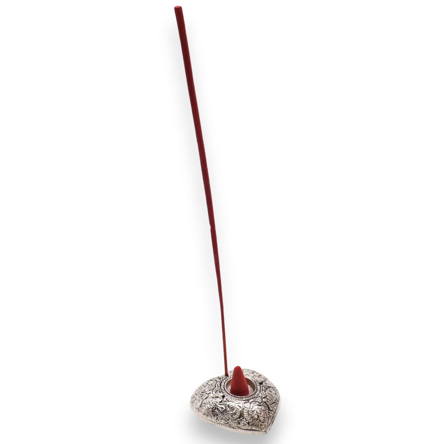 A red incense stick stands upright in an ornate silver heart-shaped holder with intricate designs against a plain white background.