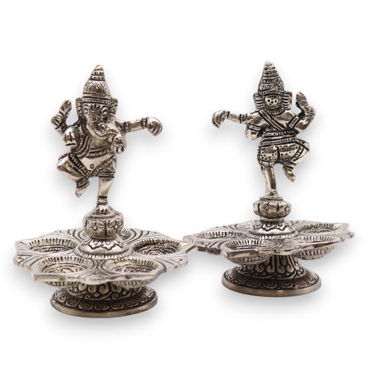 Two intricately designed metallic figures of deities stand on ornate bases with six petal-shaped sections, suggesting a traditional and cultural artistic context.