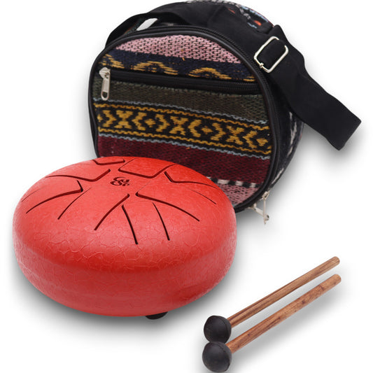 A red tongue drum sits beside a pair of wooden mallets and a round, patterned carrying bag in a colorful, textured design.