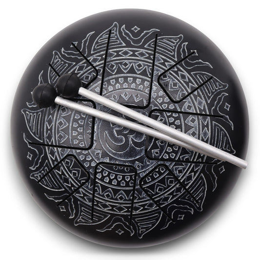 A black steel tongue drum with intricate silver mandala designs, featuring two resting mallets and an Om symbol, set against a plain white background.
