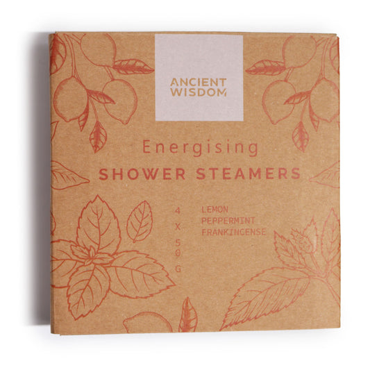 A brown cardboard package labeled "Ancient Wisdom Energising Shower Steamers" contains four 50g steamers with lemon, peppermint, and frankincense. The box features red leaf and fruit illustrations.