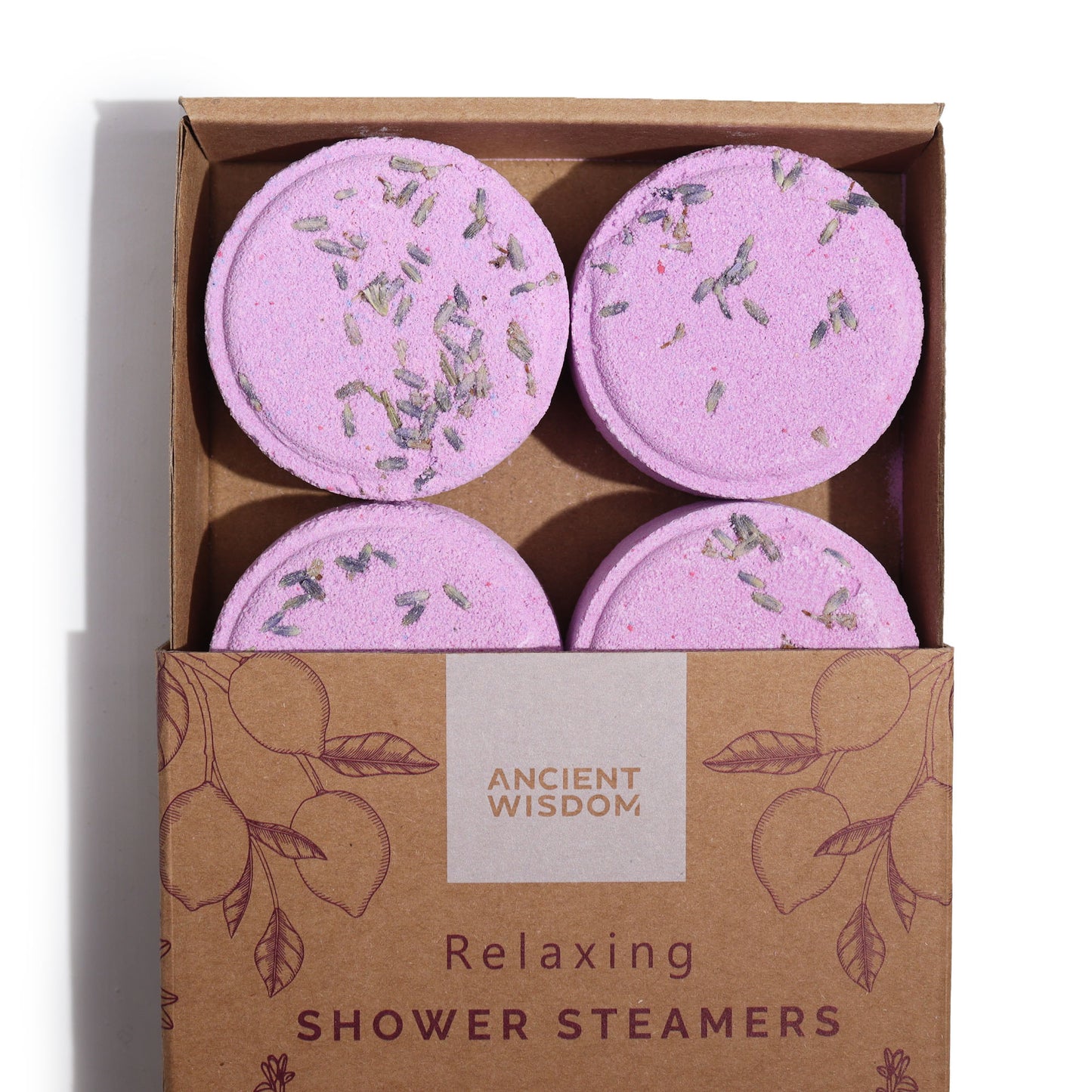 Pink lavender-sprinkled discs are arranged in a cardboard box with floral designs. Text reads: "ANCIENT WISDOM Relaxing SHOWER STEAMERS."