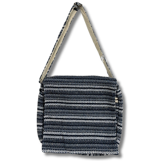 A woven shoulder bag with a chevron pattern in black and white, featuring a long strap, set against a plain white background.