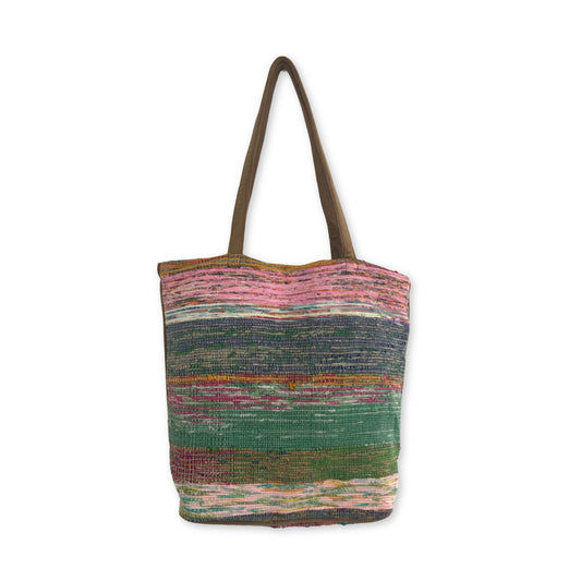 A multicolored woven tote bag featuring vertical brown handles. The bag displays horizontal stripes in pink, green, blue, and red, set against a plain white background.