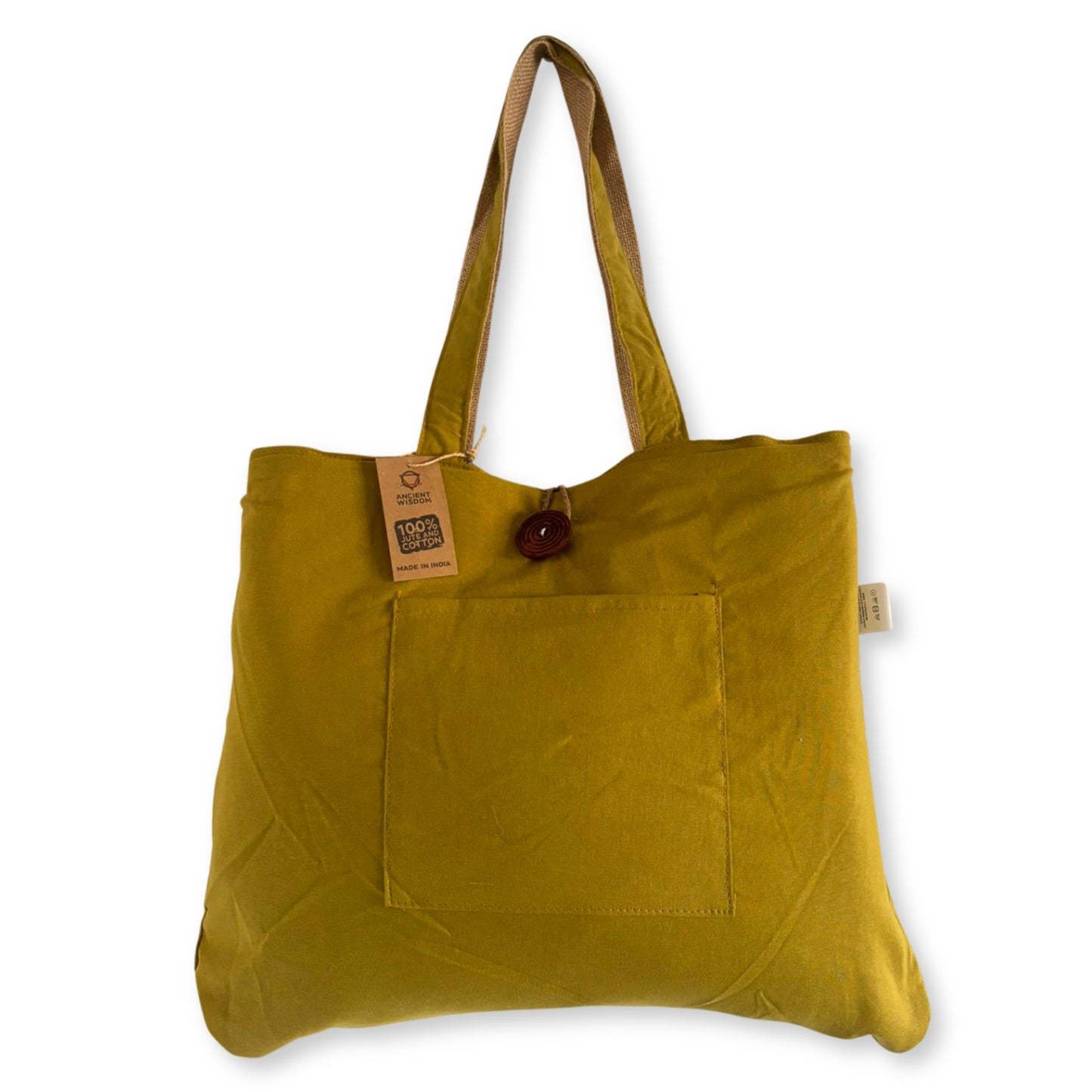A yellow tote bag has long handles and a front pocket, with a wooden button closure. Text tags show "100% Cotton" and "Made in India," against a plain white backdrop.