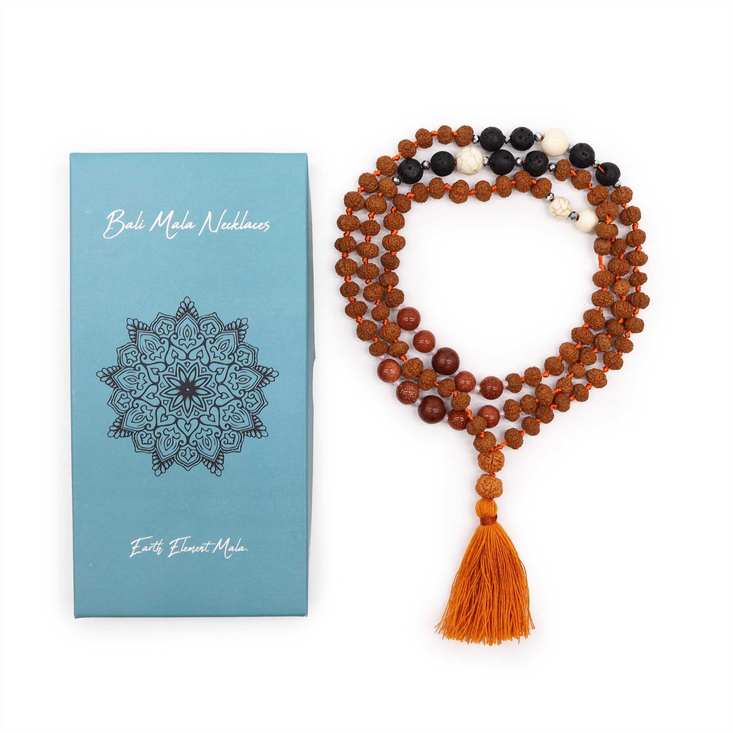 A necklace made of beaded strands with an orange tassel lies beside a blue box. The box reads "Bali Mala Necklaces" and "Earth Element Mala," featuring an intricate mandala design.