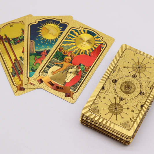 Tarot cards lie on a surface, showcasing vibrant illustrations, including one labeled "THE SUN." A stack of these gold-colored cards sits beside them.