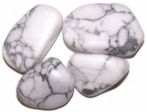 Four polished, white stones with dark grey veining sit on a white surface, grouped together.