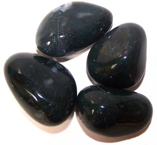 Four dark-green, smooth, polished stones are clustered together on a white surface.