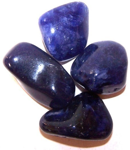 Four tumbled, rounded, polished, dark blue-purple stones are gathered on a white surface.