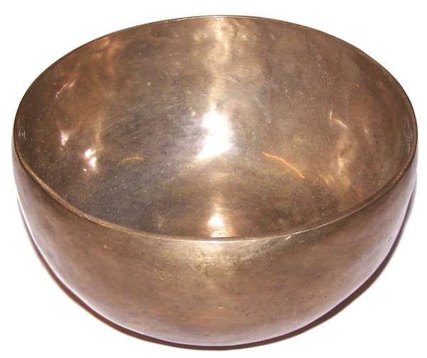 A metallic singing bowl sits empty, reflecting light on its smooth, rounded surfaces. It is placed against a plain white background, highlighting its polished, bronze-like appearance.