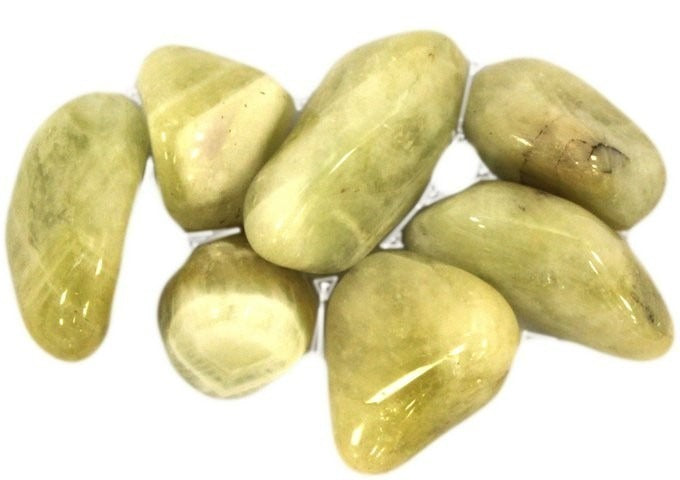Several yellow-green tumbled stones rest together on a white surface.