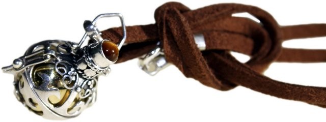 A silver, ornate pendant with an amber-colored stone hangs from a tied brown suede cord. A silver clasp connects the pendant to the cord against a white background.