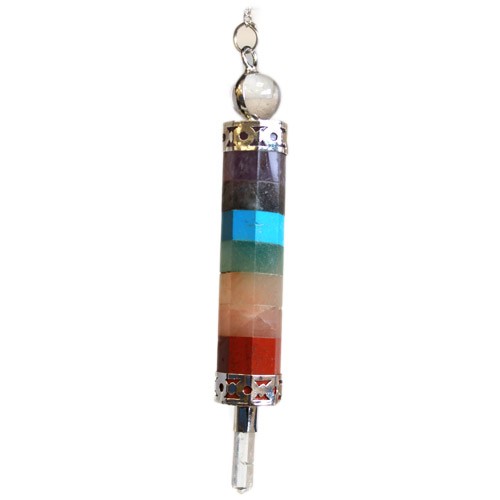 A chakra pendulum hangs vertically from a silver chain and bale. The pendulum is composed of stacked, colorful stones between two silver caps, and a clear crystal point extends from the bottom.