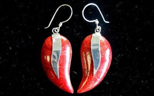 Two earrings hang against a black background, showcasing red, elongated, heart-shaped drops with silver bands across the top and silver hooks.