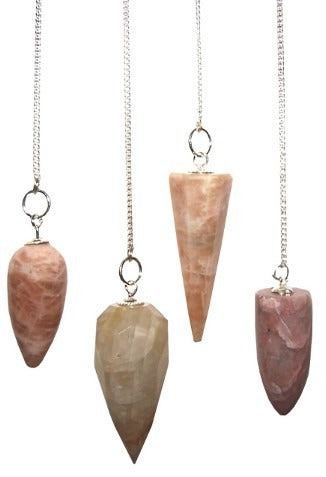 Four crystal pendulums of varying shapes (rounded, faceted, conical) and colors (beige, salmon, maroon) hang from thin silver chains against a white backdrop.