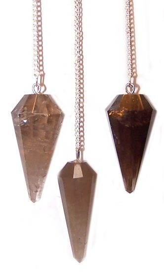 Three brown crystal pendants hang from silver chains in a white space. The pendants are multifaceted and pointed.