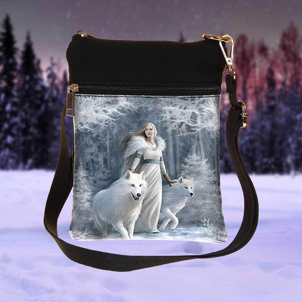 A black cross-body bag displays an image of a woman in a fur-lined dress walking with two white wolves in a snowy, frosted forest. The background is a snowy, purple-tinted landscape.