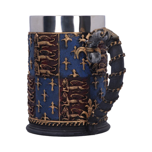 A decorative stein features a metal interior. The exterior shows a divided shield design of fleur-de-lis, and lions, with a dragon’s head atop the handle. The stein is centered against a white background.