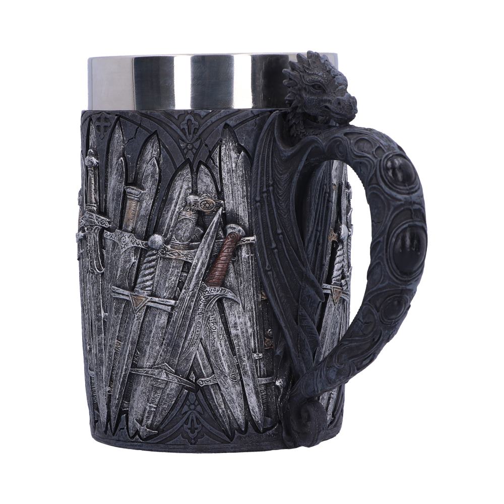 A silver-topped stein features raised sword designs on the body and a sculpted dragon whose wing forms the handle. It sits isolated on a white surface.