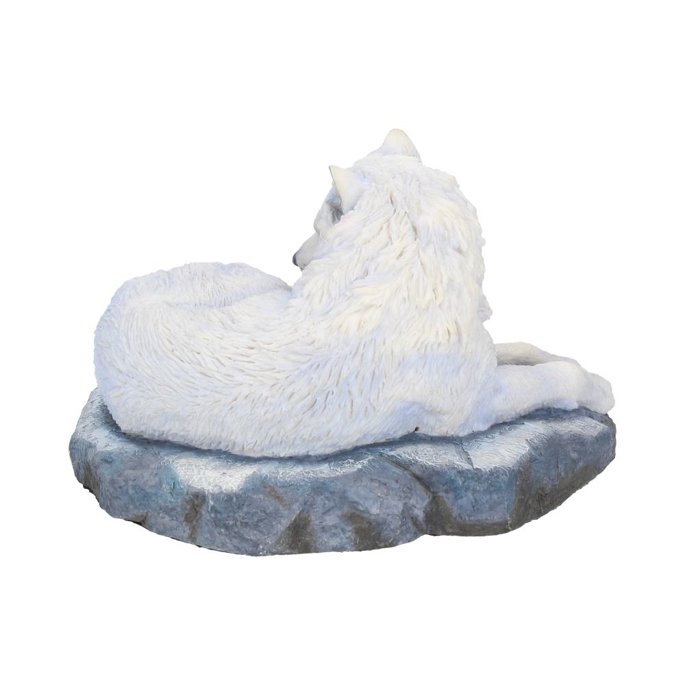 A white wolf sculpture rests peacefully, curled on a textured rock platform, with its body turned slightly away, suggesting a watchful stillness in an undefined white setting.