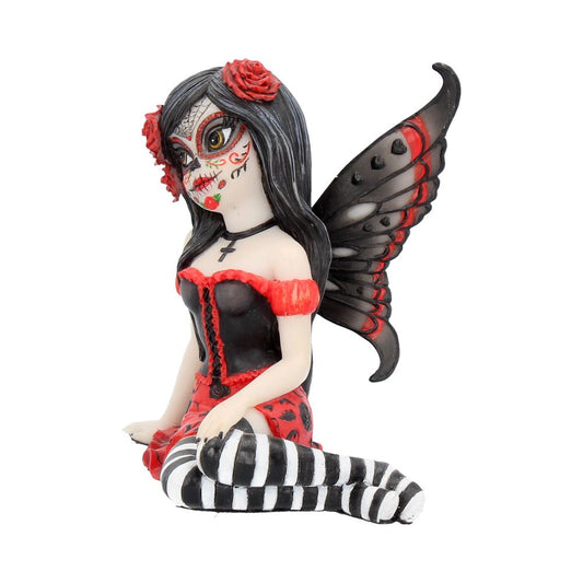 A figurine of a seated fairy with black and red wings, wearing a black corset and striped stockings, displays intricate face paint resembling Day of the Dead motifs, set against a plain backdrop.