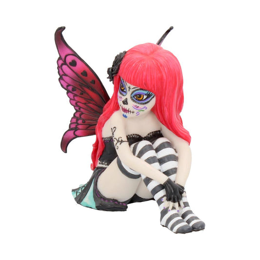 A figurine of a seated fairy with bright pink hair and butterfly wings, painted with a Day of the Dead face. The figure wears striped stockings and a dark outfit.