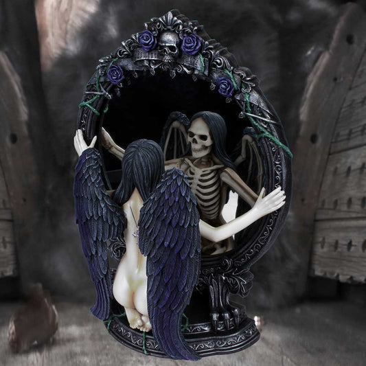 The winged figure statue kneels with arms outstretched, as a skeletal reflection with wings also outstretched appears in the ornate, rose-and-skull-adorned mirror, set against a dark background.