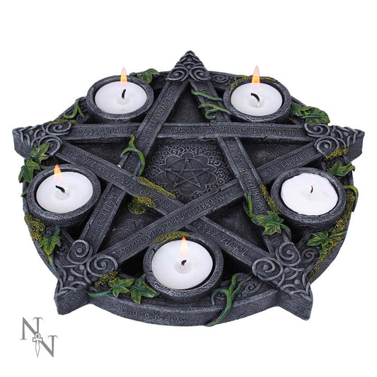Stone pentagram candle holder holding five lit tealight candles, entwined with green ivy and moss, resting on a white surface; text: 'NN' (stylized logo); illegible carved runes along the pentagram.