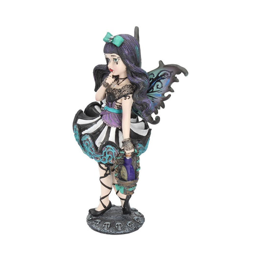 A fairy figurine stands with a finger to her lips and holds a lantern. She stands on a base with skulls, against a white background.