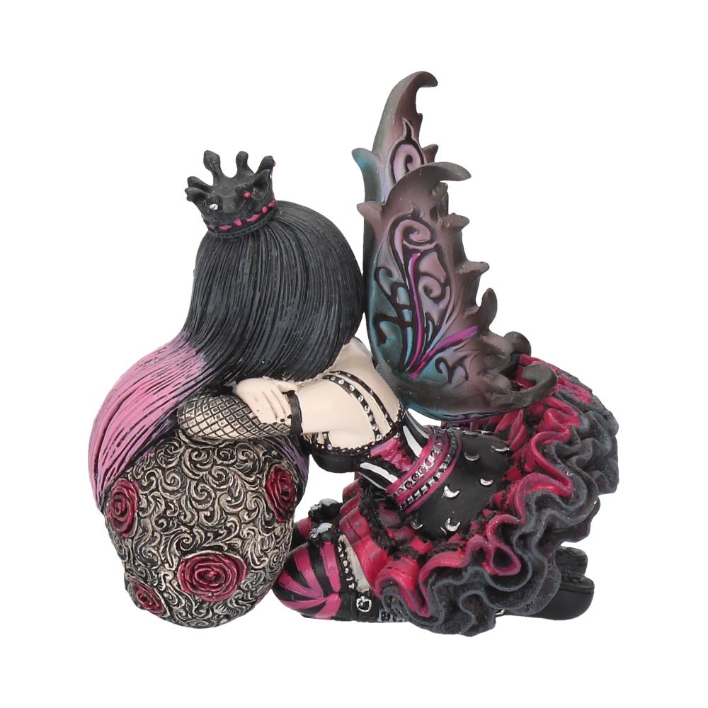A small fairy figurine with intricate black and pink wings sits curled up, adorned in a crown and detailed dress with rose patterns, against a plain white background.