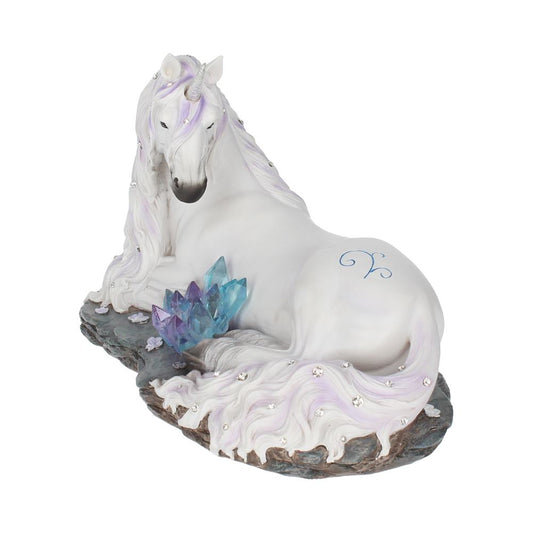 A white unicorn with a purple mane rests atop a rocky base. A cluster of blue and purple crystals sits near the unicorn, with a blue zodiac symbol on its rear.