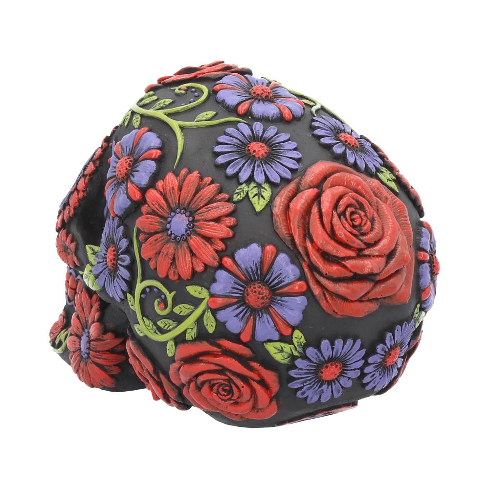 A black skull adorned with vibrant red roses and purple flowers is intricately designed, showcasing a colorful floral motif.