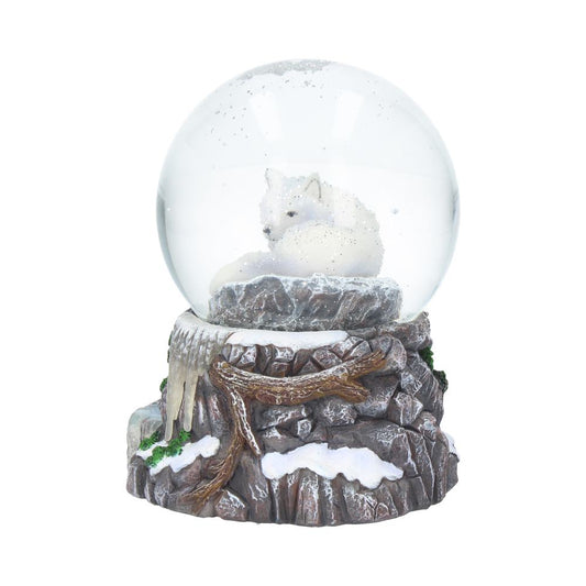 A white wolf rests inside a clear snow globe. The globe is set atop a rocky, snow-covered base with wooden branches and icicles.