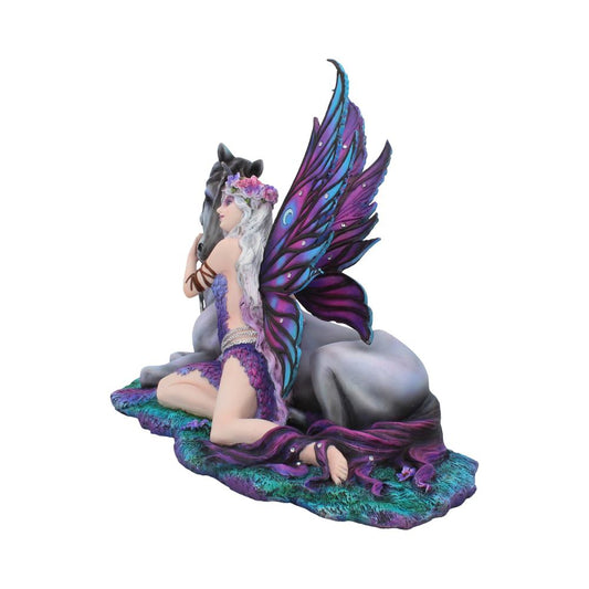 A fairy with purple wings kneels beside a resting unicorn. The fairy wears a floral headpiece and purple attire, set on a textured base resembling grass.