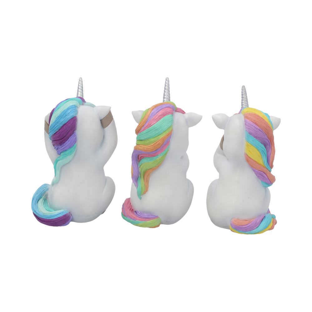 Three white unicorn figurines with rainbow manes sit in a row on a white surface, each covering a different part of their face: eyes, ears, and mouth.